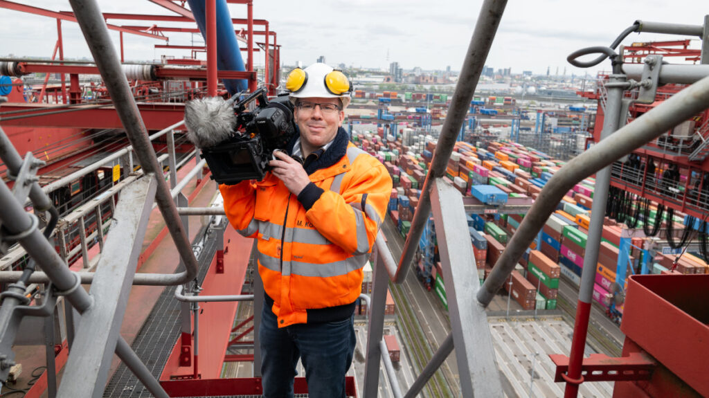 Mann mit Kamera auf einer Containerbrücke